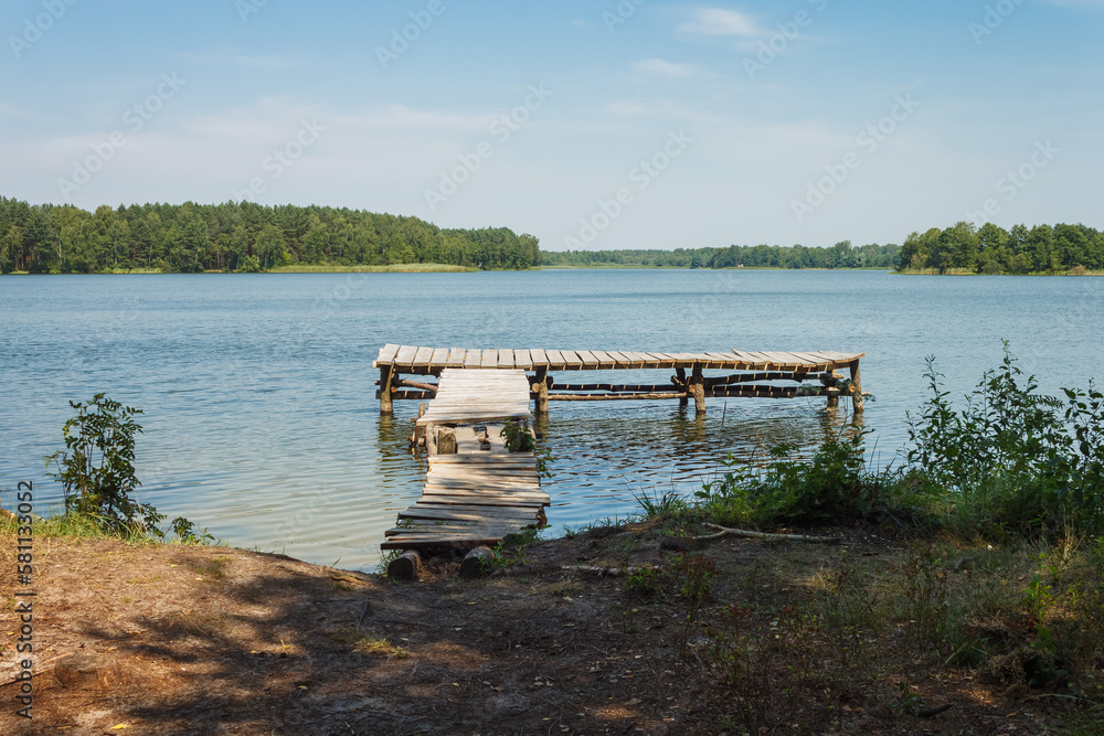View of the lake with an old wooden pier. Lake in the summer