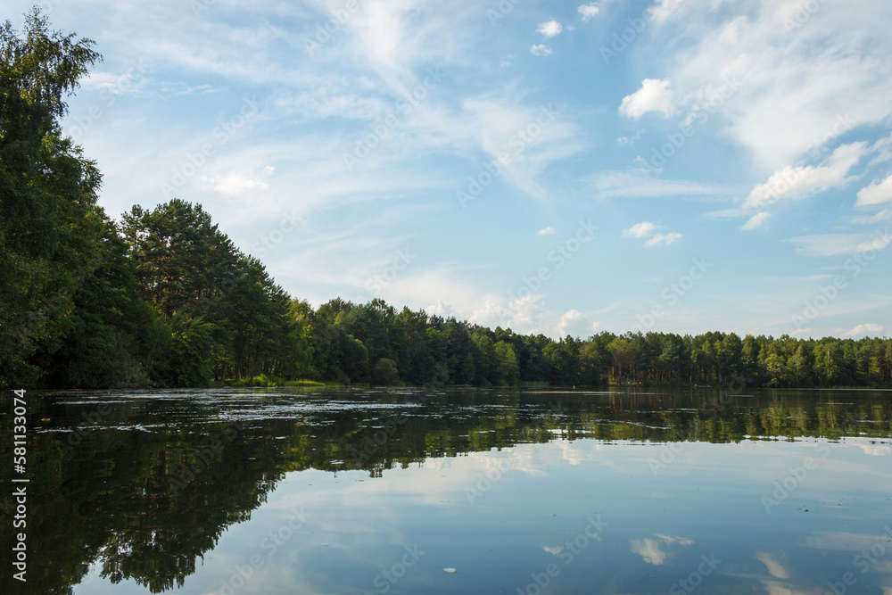 Landscape with a forest lake. Reflection of clouds in the lake. Summer