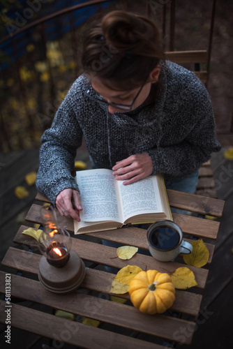 Cozy autumn evening. The girl is sitting at the table with a book.