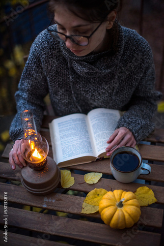 Still autumn life with books and coffee . Cozy autumn evening. The girl is sitting at the table with a book.