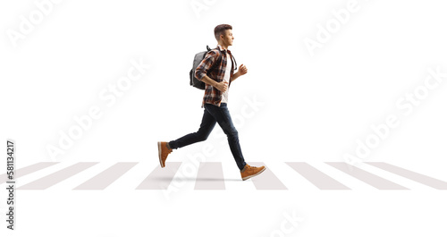 Full length profile shot of a male student running over pedestrian crossing