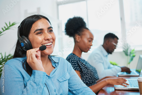 Photography A friendly South Asian woman talks to client on headset, support agent helpdesk