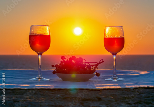 Two glasses of wine and grapes at sea sunset