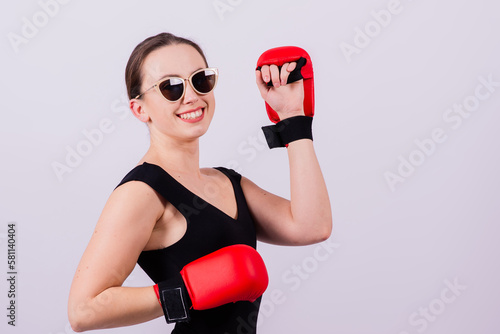 Seductive female boxer with athletic beautiful figure in black swimsuit gloves on gray background photo