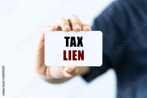 Tax lien text on blank business card being held by a woman's hand with blurred background. Business concept about tax lien. photo