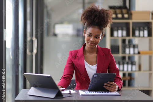 Attractive african american businesswoman working with tablet and documents on office desk.