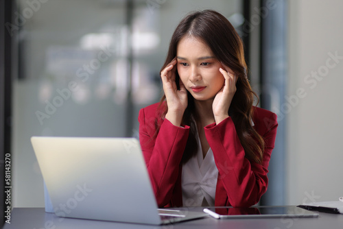 Serious businesswoman working with laptop on desk in office, woman thinking to solve a problem. Businesswoman is stressed and worried about unsuccessful work.