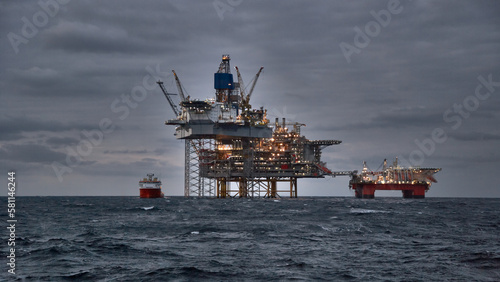 Picture of offshore oil and gas production in the sea in stormy weather at dusk.\
Jack up, semi submersible rigs crude oil production in ocean.