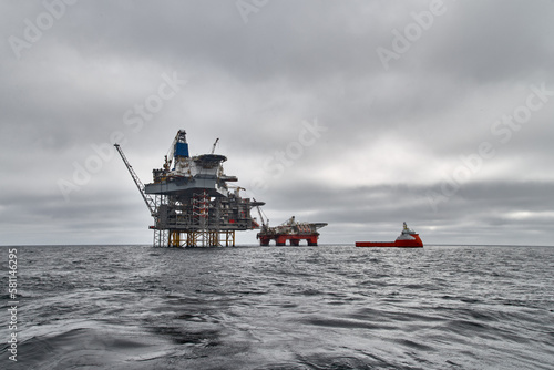 Jack up drilling rig, semi submersible platform and supply vessel on a dark cloudy day in the sea. North Sea oil and gas.  photo