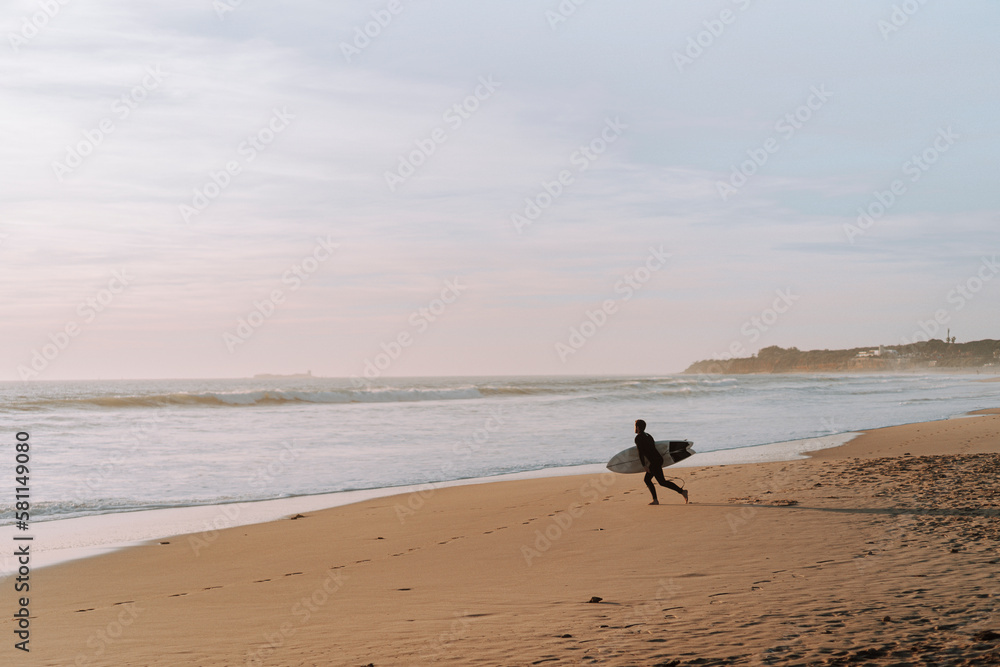Silueta de surfista entrando en el agua al atardecer en playas de andalucia