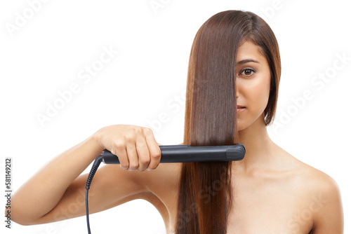 Straightening her hair for a great date. A young woman straightening her hair.