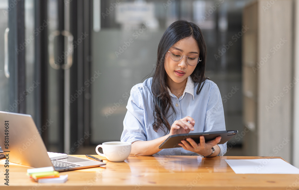 Beautiful young Asian woman working on laptop computer while sitting at the plan office space after working hours, Asian woman drinking coffee Beautiful young Asian woman working on laptop computer while sitting at the plan office space after working hours, Asian woman drinking coffee
