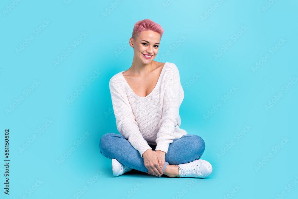 Full length photo of sitting pretty woman folded legs wear white long sleeve denim jeans lovely person posing isolated on aquamarine color background Full length photo of sitting pretty woman folded legs wear white long sleeve denim jeans lovely person posing isolated on aquamarine color background