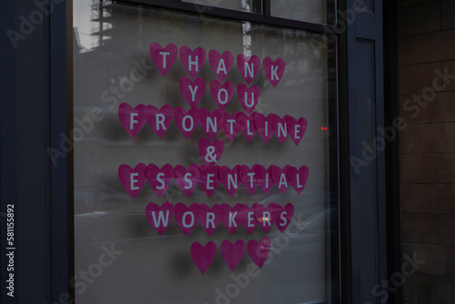 Sign thank you frontline and essential workers made of hearts in store window during covid 19 pandemic outbreak lockdown quarantine.