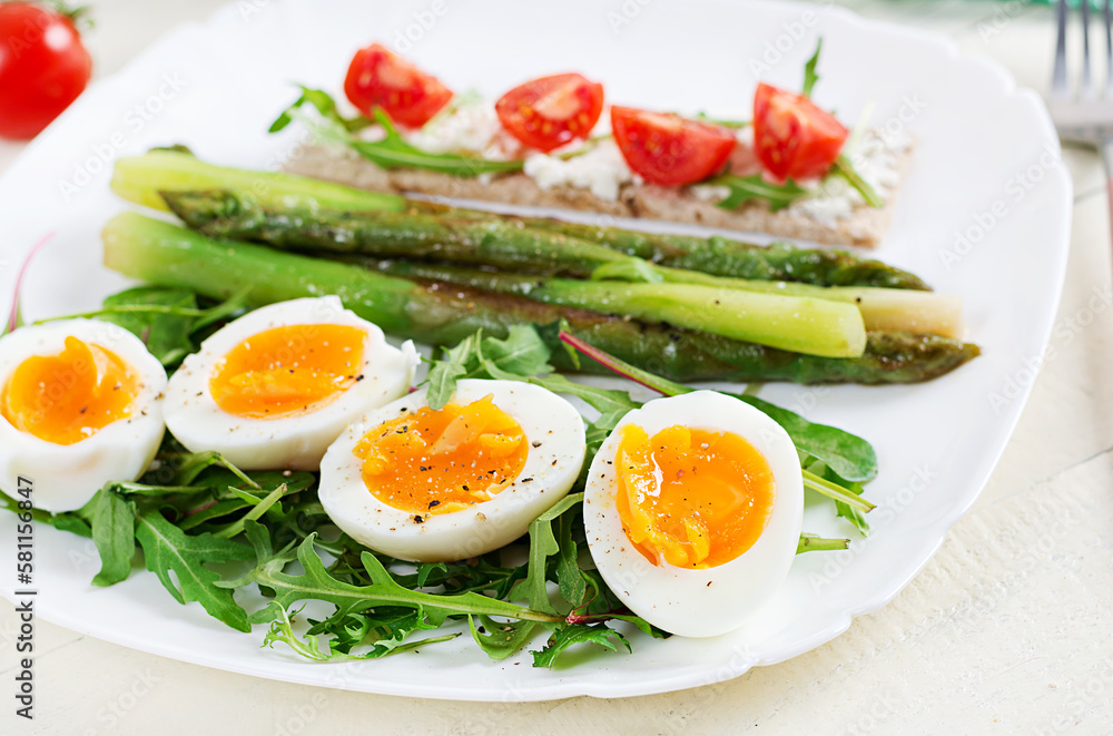 Green asparagus with boiled eggs and sandwich cream cheese on a white plate. Green asparagus with boiled eggs and sandwich cream cheese on a white plate.