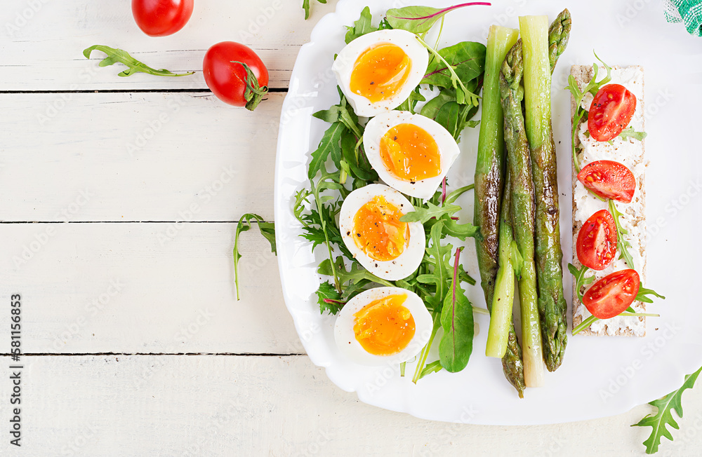 Green asparagus with boiled eggs and sandwich cream cheese on a white plate. Top view, flat lay Green asparagus with boiled eggs and sandwich cream cheese on a white plate. Top view, flat lay