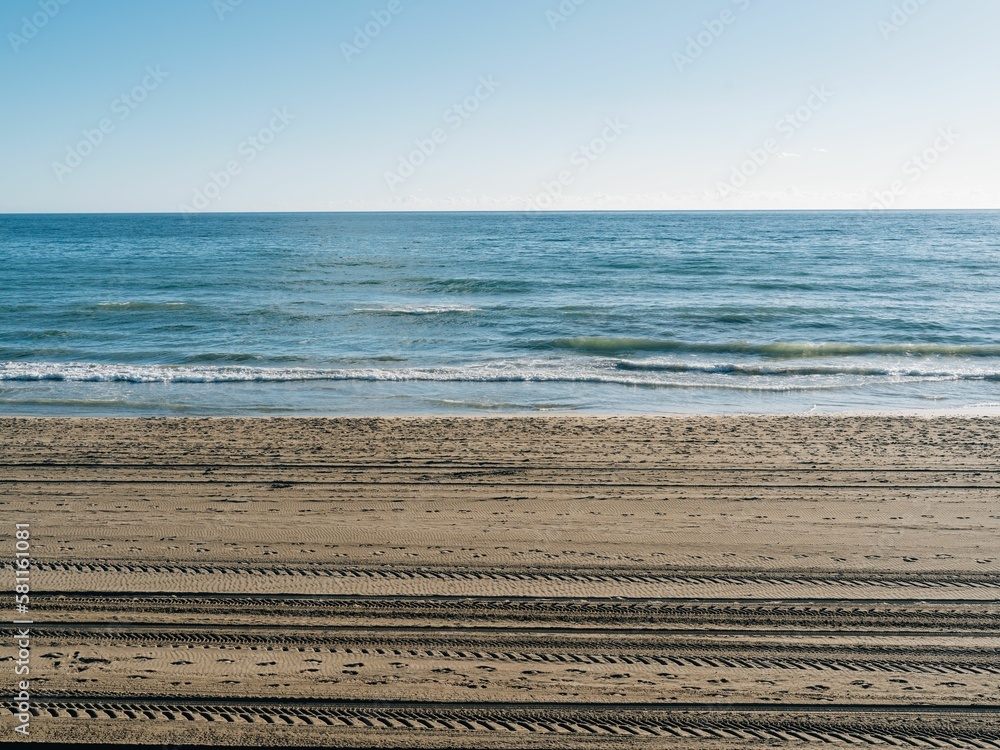 Naklejka premium Tire tracks and footprints on a sandy beach on a sunny day in Marbella, Spain