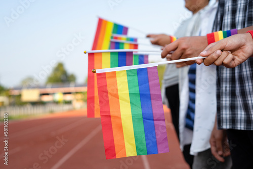 people hands holding lgbt rainbow flags stand in row, concept for lgbt parade,lgbtq happy pride month, movement of lgbt equality community