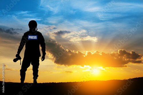 Photojournalist silhouette documenting war or conflict. Photojournalist at sunset.