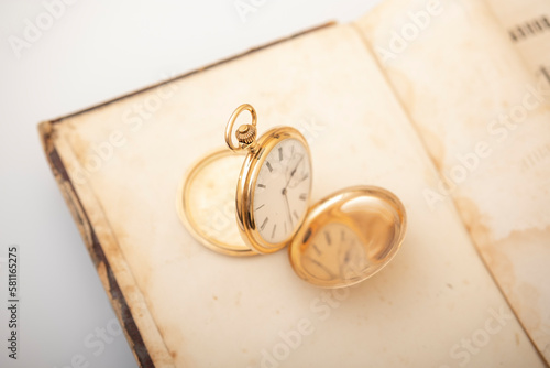 Vintage gold pocket watch on an open old book.