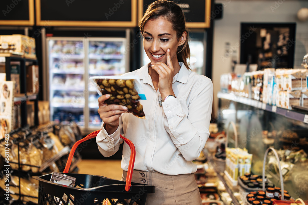 Beautiful young and elegant woman buying some healthy food and drink in modern supermarket or grocery store. Lifestyle and consumerism concept.