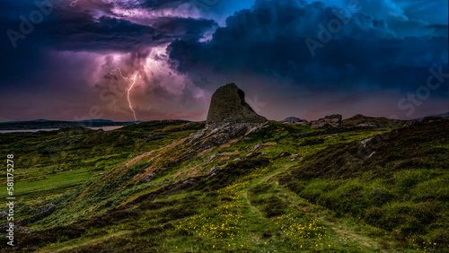 Ruined moorland castle tower during lightning storm