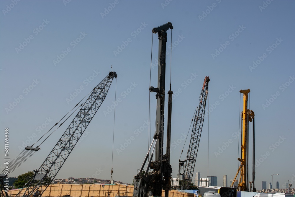Cranes and heavy industrial machines in a construction site against the sky Cranes and heavy industrial machines in a construction site against the sky