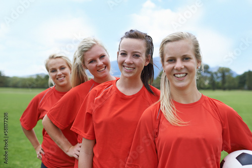 Were ready to win. Portrait of a young female soccer player and her team mates standing behind her.