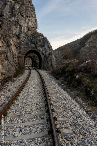 Train line cutting through the mountain. Old railroad tunnel on the railway. Winter Serbian mountain landscape with railway tunnel.