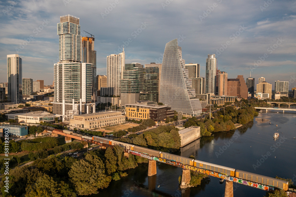 Fototapeta premium Downtown, Austin Texas skyline and cityscape with passing train along bridge over Lady Bird Lake during golden hour sunset