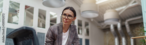Portrait of professional businesswoman in glasses standing in modern office with documents