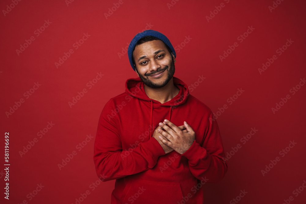 Indian man smiling and holding hands on his chest isolated over red background Indian man smiling and holding hands on his chest isolated over red background