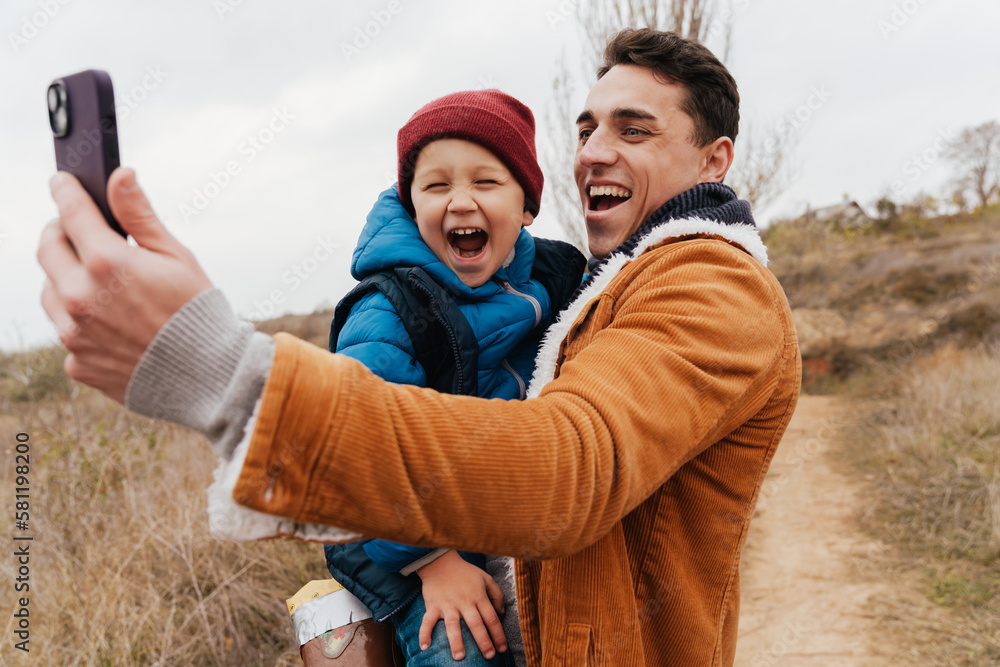 Cheerful father taking selfie with his son while spending time together in nature Cheerful father taking selfie with his son while spending time together in nature