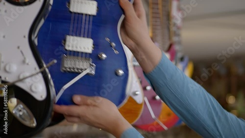 a man chooses a blue electric guitar in a music store