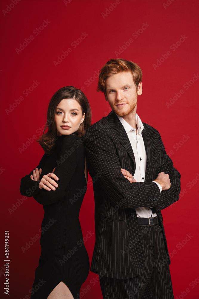Couple standing back to back isolated over red background Couple standing back to back isolated over red background
