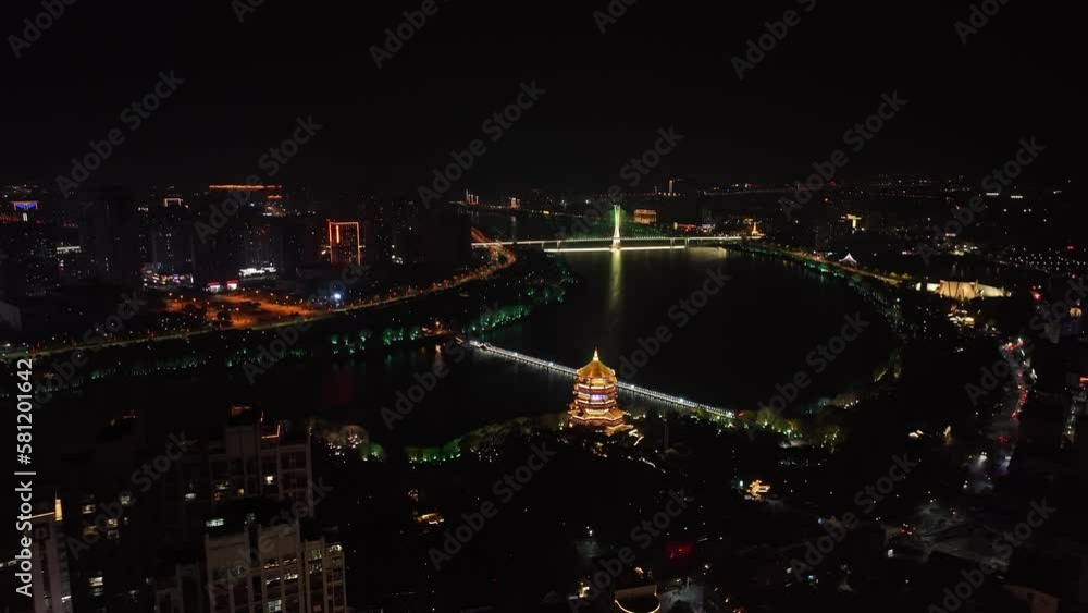 view of glowing ancient tower by lake at night view of glowing ancient tower by lake at night