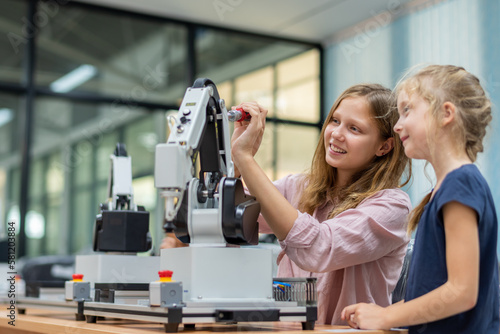 Kid female teen child enjoy Machine Learning Robot arm is Moving Under Control robot at technology class, stem education robot arms for digital automation software for artificial intelligence ai