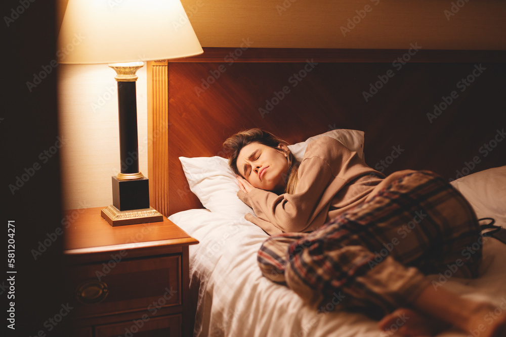 Unhappy woman lying on one half of empty bed alone, feeling lonely after quarrel with boyfriend, break up or divorce, upset young female suffering from bad dreams or insomnia at night near lamp. Unhappy woman lying on one half of empty bed alone, feeling lonely after quarrel with boyfriend, break up or divorce, upset young female suffering from bad dreams or insomnia at night near lamp.