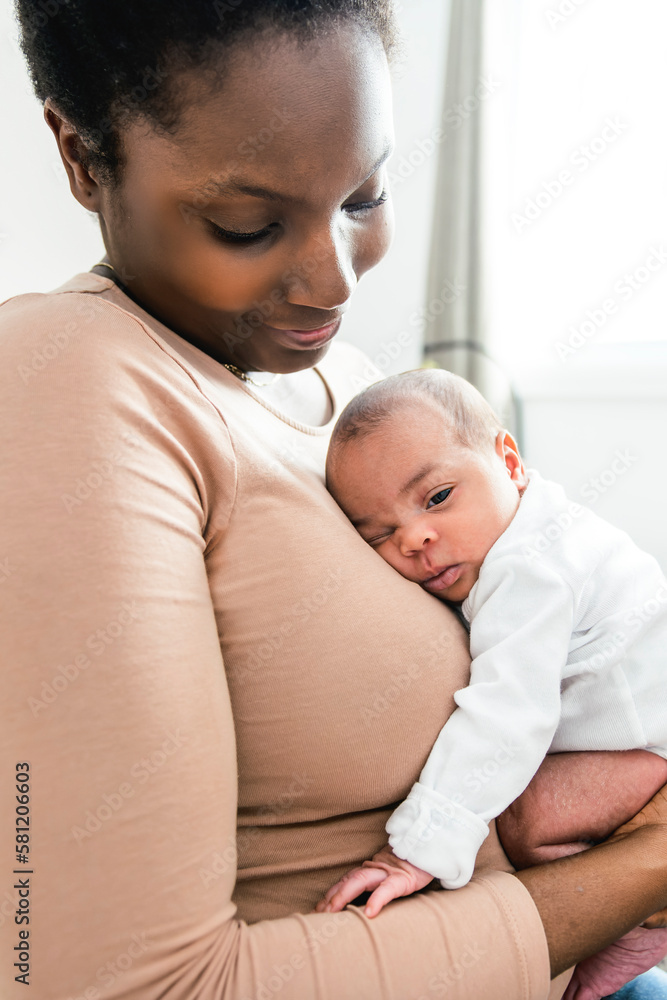 A Portrait of a beautiful black mother, with her nursing baby close to a window A Portrait of a beautiful black mother, with her nursing baby close to a window