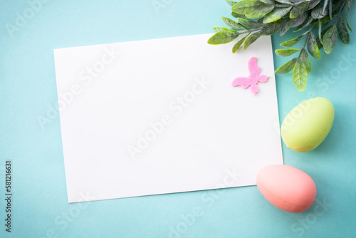 Easter background or greeting card on blue. Eggs, spring leaves and butterfly. Flat lay with copy space.