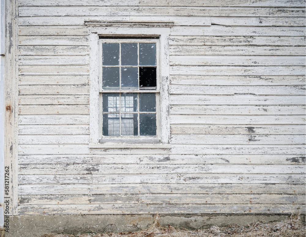 Fototapeta premium Old house exterior with old wooden boards and broken window. White painted wood siding with antique finish. Snow falling