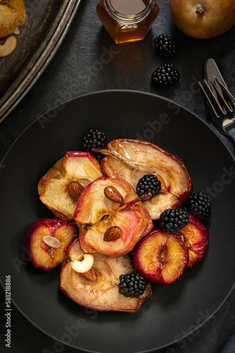 Baked apples, pears and plums with almonds, nuts and honey. Vintage tableware. Delicious and healthy dessert. Top view.  Low key photography.