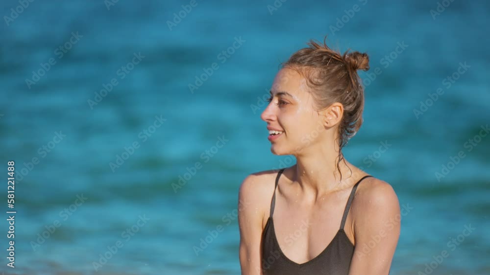Hot attractive smiling woman in wet black swimmsuit lies on the shore of the sea in splashing waves. Hot attractive smiling woman in wet black swimmsuit lies on the shore of the sea in splashing waves.