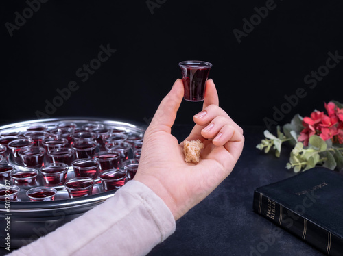 Closeup of young woman taking communion from small cups on black background