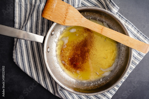 Brown Butter in a Stainless Steel Skillet with a Wooden Spatula: Overhead view of browned butter in a frying pan on a kitchen towel