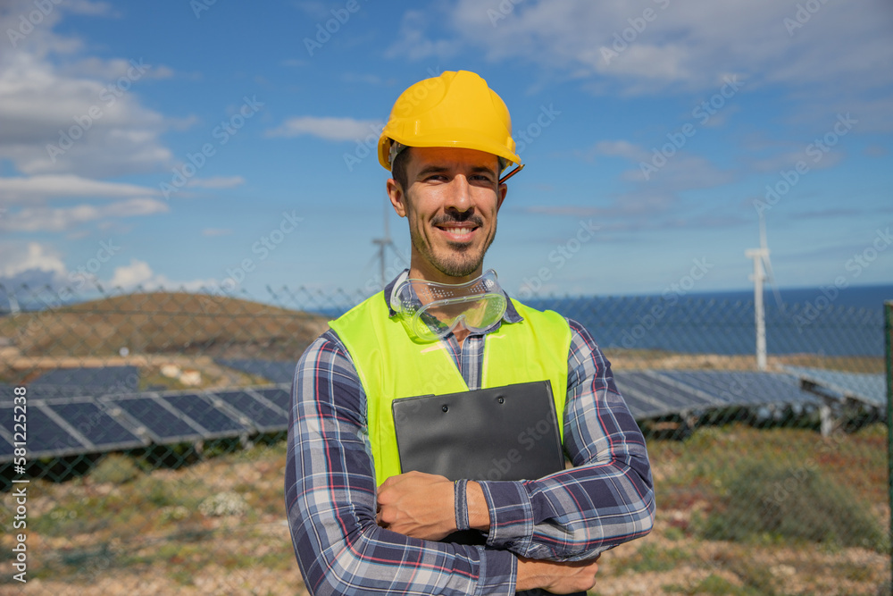 An engineer with his arms folded holds a folder at a solar power plant