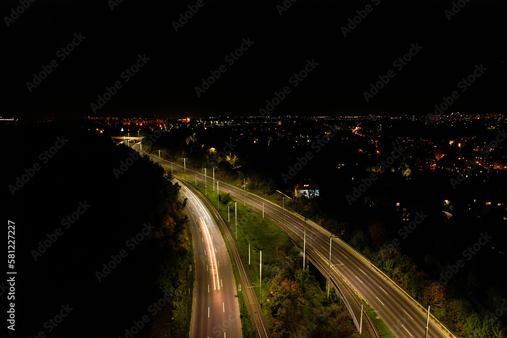 Top down view to road. Romantic night aerial photo of cars traveling. The light on the road at night in city. Background scenic road drone view. Tram railways