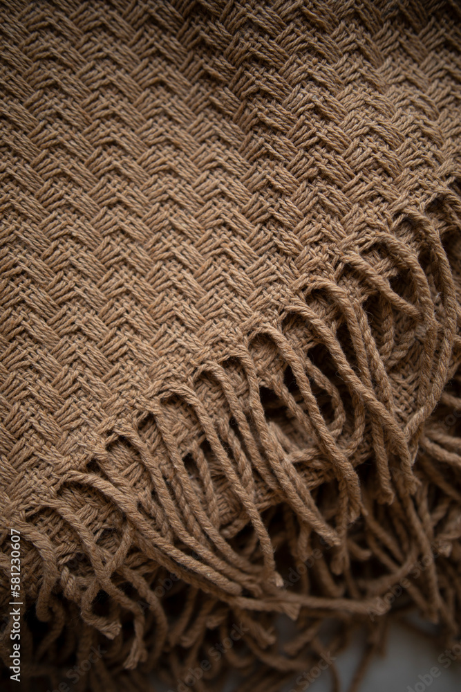 beige woolen plaid from llama wool close-up. knitting details of a woolen plaid with tassels top view. beige woolen plaid from llama wool close-up. knitting details of a woolen plaid with tassels top view.