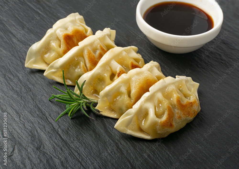Gyoza Chinese Dumplings, Fried Vegetable Jiaozi, Chicken Momo Pile, Asian Gyoza Group on Black Stone Plate Gyoza Chinese Dumplings, Fried Vegetable Jiaozi, Chicken Momo Pile, Asian Gyoza Group on Black Stone Plate