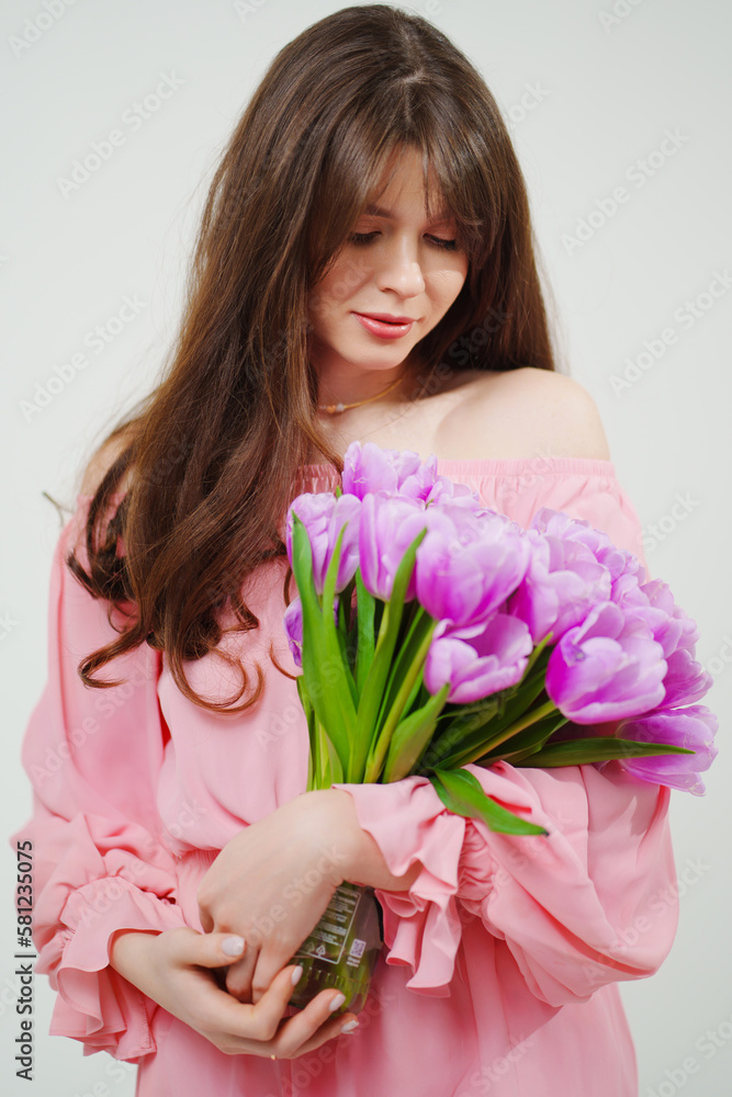 beautiful young brunette woman with long hair in pink with a bouquet of tulips. beautiful young brunette woman with long hair in pink with a bouquet of tulips.
